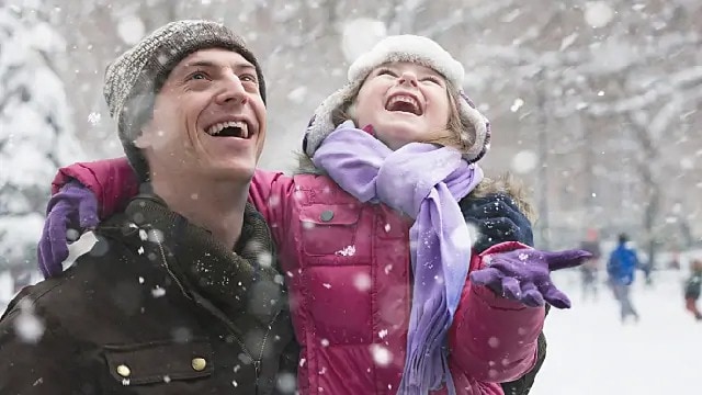 father and daughter laughing in the snow