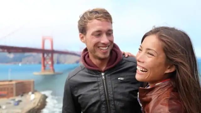 couple smiling by a bridge