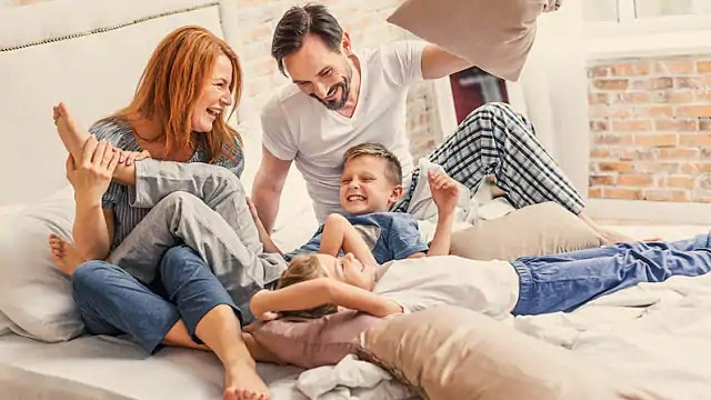 Family of four laughing while playing with pillows