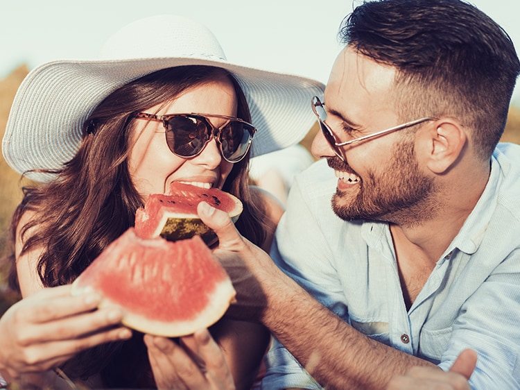 A couple eating a watermelon outdoors