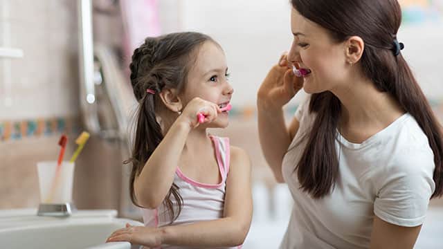 Mom is teaching daughter how to brush