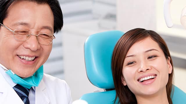 Senior male Dentist and female patient smiling at something off camera.