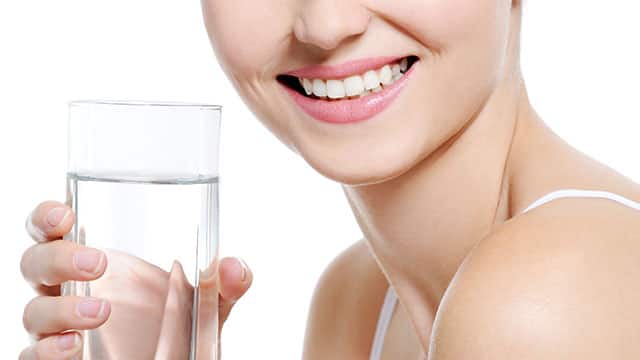 A woman is holding a glass of water