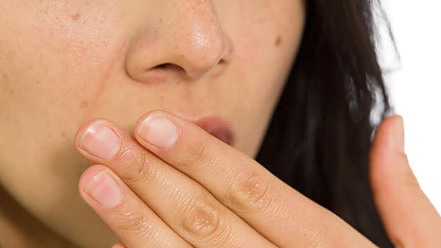 A close up of woman's hand over her mouth