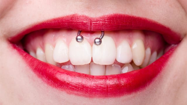 Close-up of a woman with a gum piercing