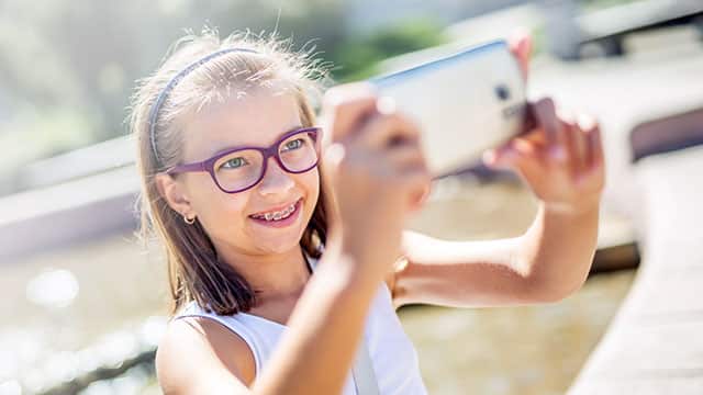 young girl with braces and glasses laughing for a selfie