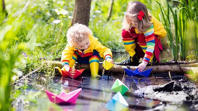 Kids playing with colorful paper boats in a park