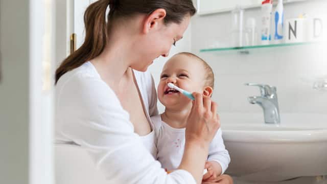 A mother brushing her baby's teeth