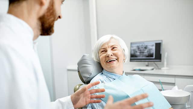 A senior woman with healthy smile sitting during the consultation with dentist at the dental office