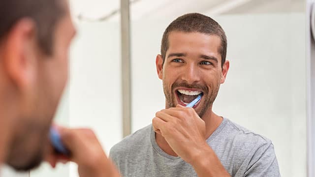 Happy man brushing teeth