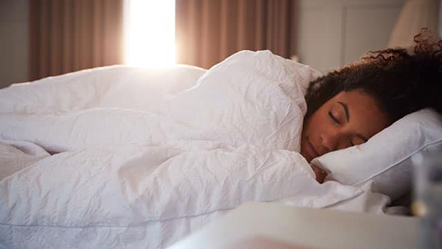 Peaceful Woman Asleep In Bed As Day Break Through Curtains