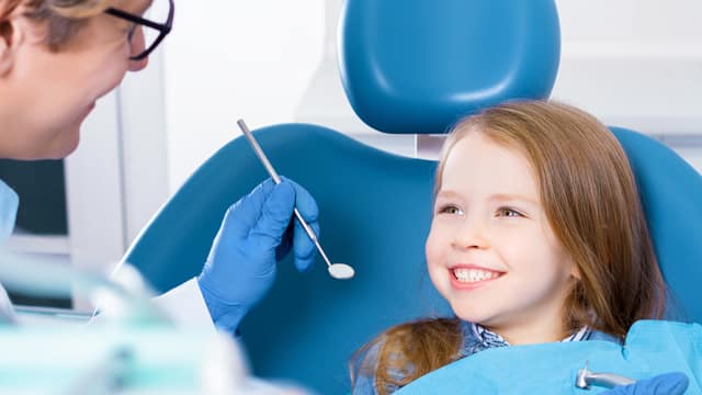 Smiling little girl about to be examined by a dentist