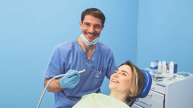 orthodontist examining a patient's teeth while smiling