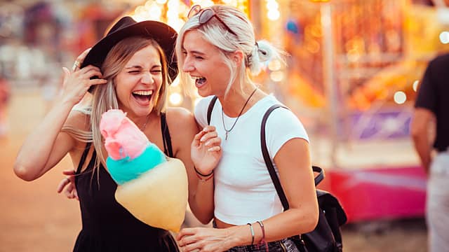 two friends eating cotton candy and laughing