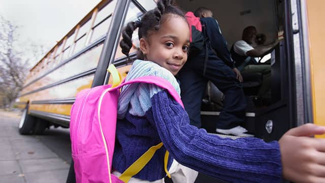 Little girl with backpack on boarding school bus