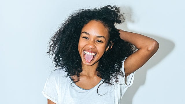 A teen girl with curly hair showing her tongue