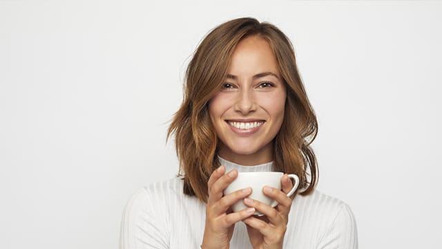 portrait of happy young woman with cup of coffee