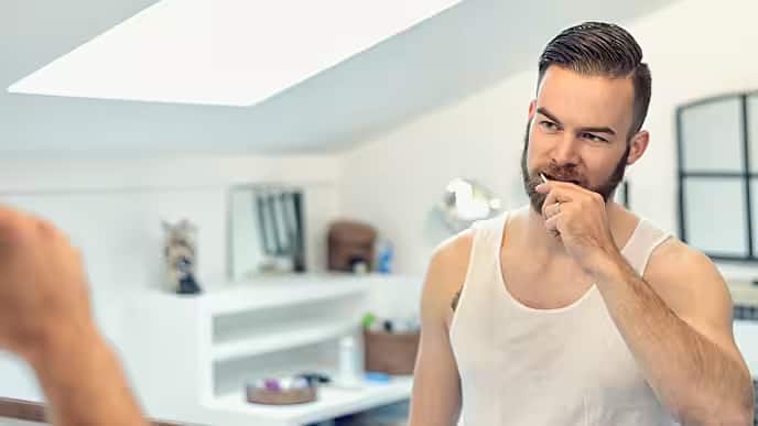 bearded man brushing his teeth