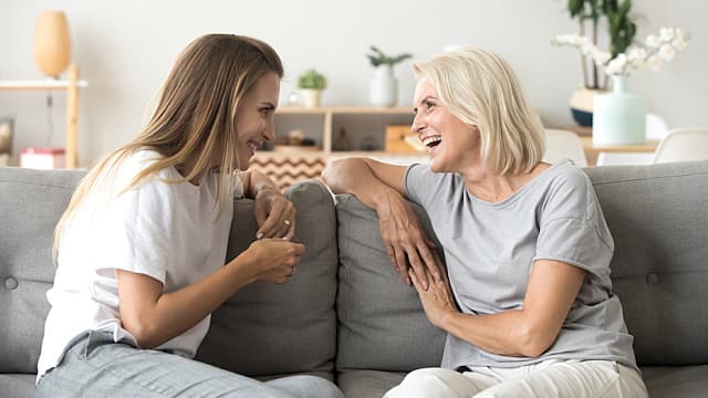 Cheerful old mother and young adult daughter talking laughing to