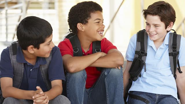 three student boys smiling sitting down