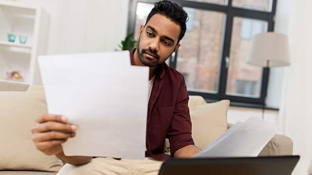 upset man with laptop and papers at home