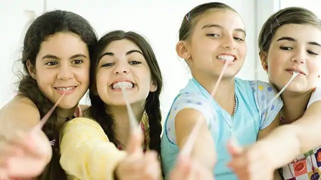 Four young girls pulling gum from their mouths