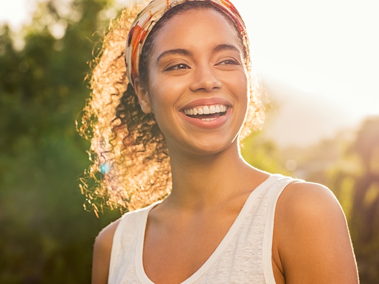 A young woman smiling outside during sunrise