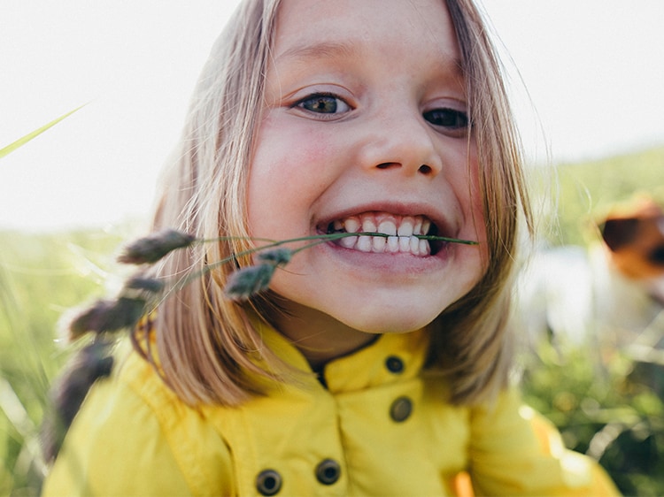 toddler smiling with wheat between teeth