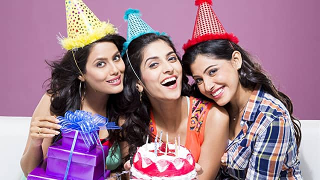 three women smiling while wearing a party hat celebrating