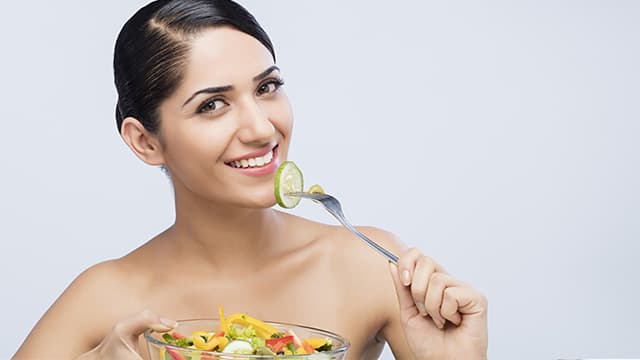 woman smiling while holding a bowl of salad