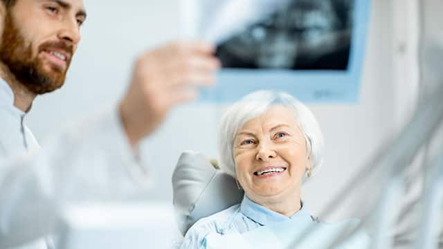 An elder woman during the consultation with a dentist showing panoramic x-ray in the dental office