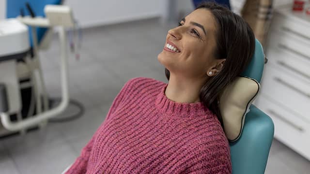 A young woman smiling while sitting on the dentist's chair and waiting for her teeth treatment
