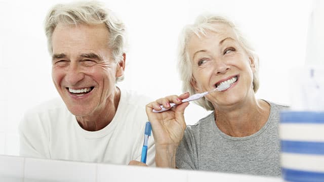 Happy senior couple, brushing teeth in the bathroom