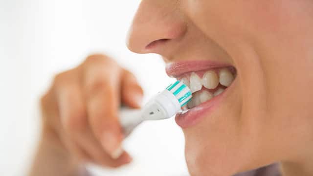 A close up of a woman mouth brushing her teeth