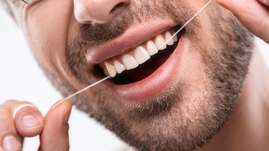cleaning between the teeth with a floss threader - colgate in