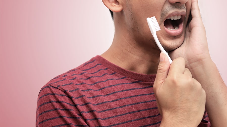 Man feel tooth pain while brushing, indicating a tooth cavity