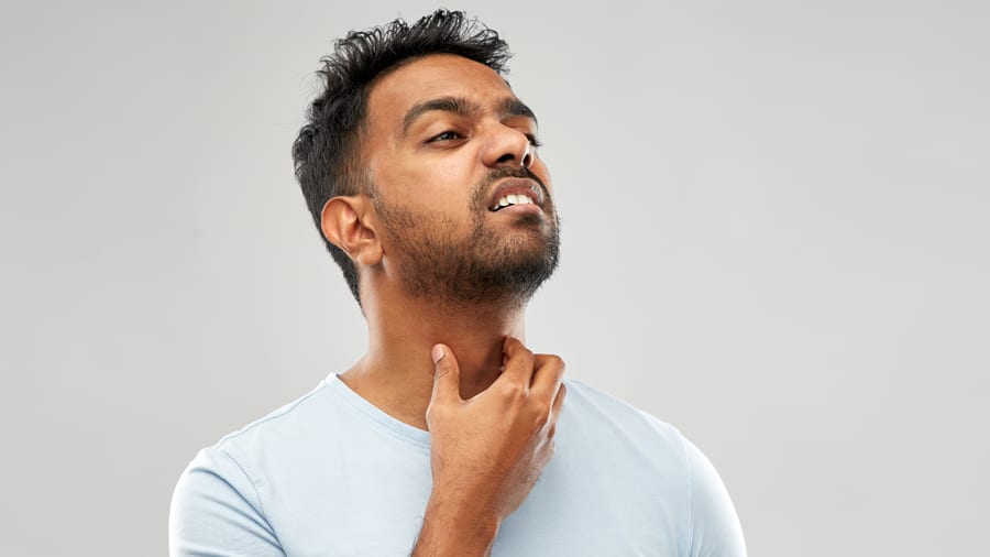 Man with hand on throat, signaling sore throat
