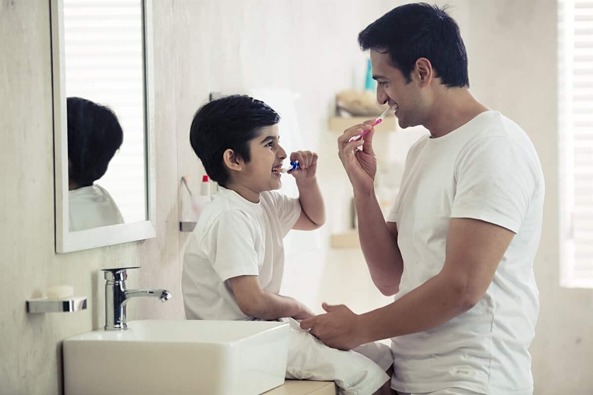Man brushing his teeth with his son