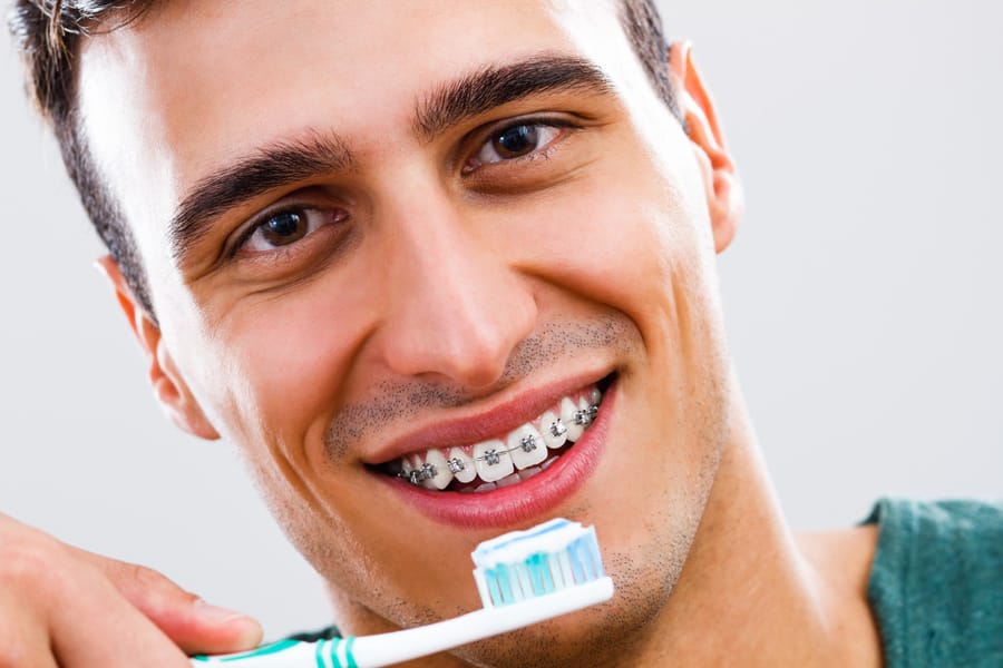 Hombre con brackets cepillándose los dientes