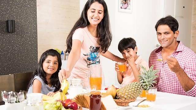 Happy indianasian young family eating healthy breakfast