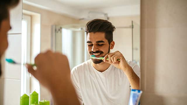 Young man is brushing his teeth