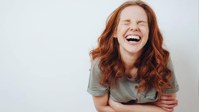 A young woman is laughing indoors