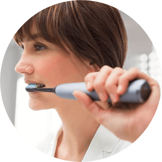 Mujer utilizando un cepillo de dientes electrico