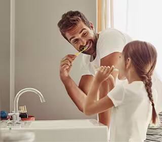 พ่อและลูกสาวกำลังแปรงฟันที่อ่างล้างหน้า