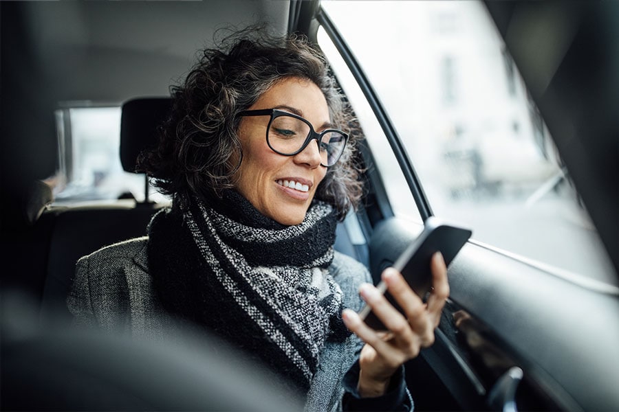 Mature businesswoman using phone while traveling by a taxi