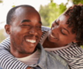 smiling young couple where one is piggybacking on the other person in a garden, eyes closed