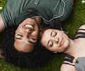 Young couple listening to music while laying on the grass