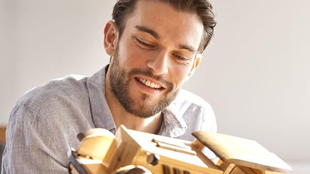 Hombre sonriendo mientras ve un tren de juguete