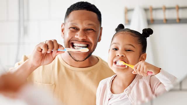 father and daughter brushing their teeth