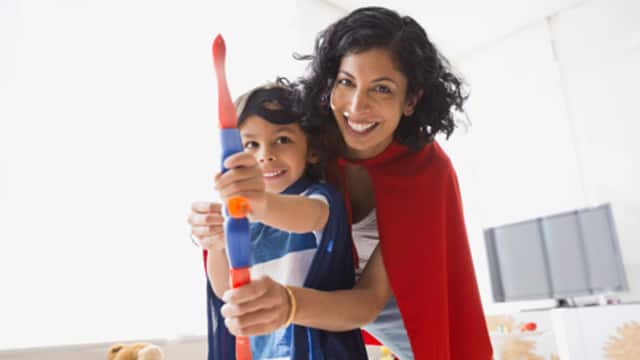 mother smiling while playing with her son with toy bow